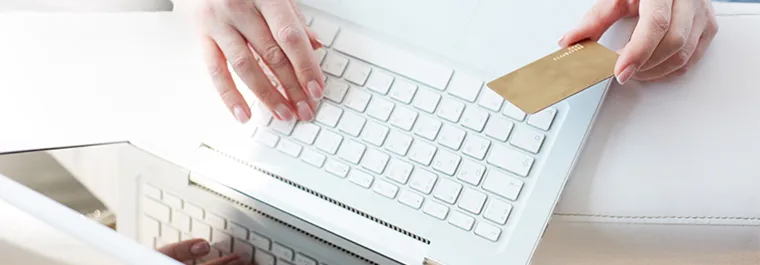 Woman completing the transaction on a laptop with a credit card in hand